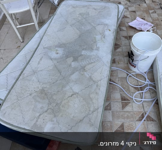 מזרן מלוכלך עם דלי וכלי ניקוי על רצפה מרוצפת